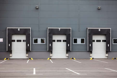 Modern truck loading bays with overhead doors. Empty area, close gatesの写真素材