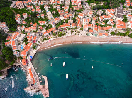 City sea shore with beach and pier next to dwelling houses. Town of Petrovac. Adriatic sea....