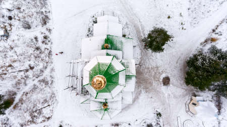 Green roof of church with golden dome and cross covered with snow. Top view. Winter