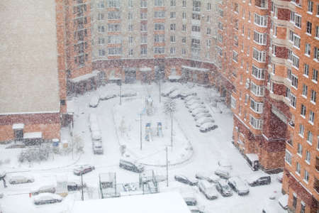 Snowfall is in the city, high-rise building inner yard with parked cars. WInter is  in RUssiaの写真素材