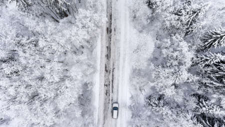 One car driving through the winter forest on country road. Top viewの写真素材