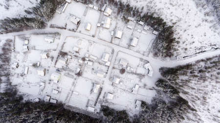 Top view at empty Russian village in wild wintry forest. Snow covered roofs, roads and courtyards. Karelia, Russiaの写真素材