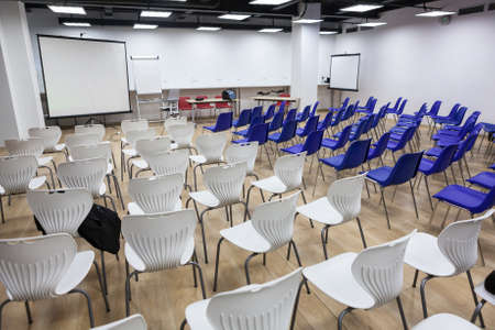 Lot of white and blue chairs are in meeting room. Hall is ready for conference or seminar