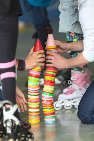 Close up view of human hands building plastic color cones on rollerskating playground