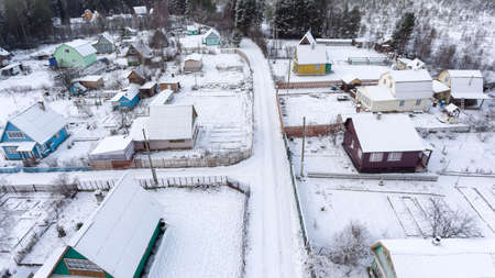 Top view at empty Russian snowy village in wintry forest. Snow covered earth lots, roofs and roads. Karelia, Russiaの写真素材