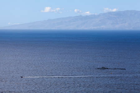 Small motorboat passing across Atlantic ocean. The Gomera island on horizon, aerial view, Tenerife, Canary islands, Spainの写真素材