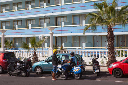 LOS CRISTIANOS, TENERIFE, CANARY, SPAIN - CIRCA JAN, 2016: Motorcycle police officer stop young man on scooter on the city street. Mobile police with motorbikes is in Tenerife islandのeditorial素材