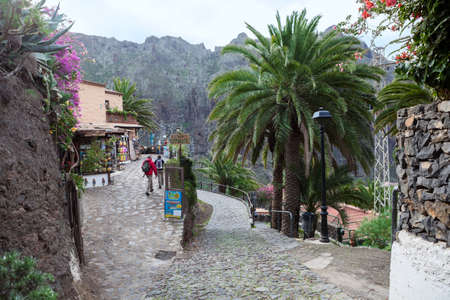 MASCA, TENERIFE, SPAIN - CIRCA JAN, 2016: Group of hikers begins their walk from the start point in beautiful paved streets of village. Masca village is a famous tourist place with start of hiking trail through the gorgeのeditorial素材