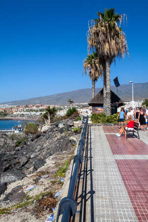 COSTA ADEJE, TENERIFE, SPAIN-CIRCA JAN, 2016: European senior people walk on the promenade with view at the Atlantic ocean. Torviscas and Fanabe are city resorts with grey sandのeditorial素材