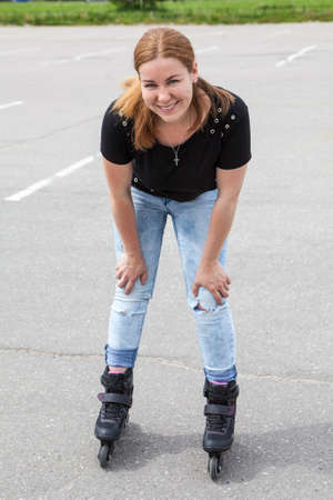 Happy and smiling young woman riding on roller-skates in urban parkの写真素材