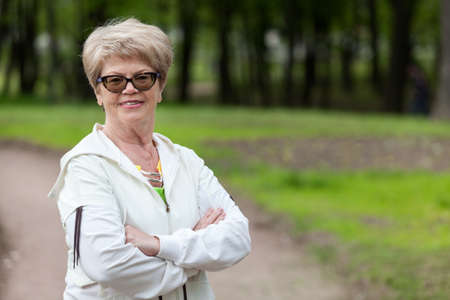 Smiling elder coach and trainer woman standing with crossed arms at train, copyspaceの写真素材