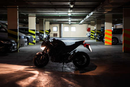 Silhouette of running engine motorcycle standing in the mile of dark underground parking. Light is turning onの写真素材