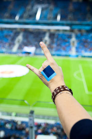 Female fan gesturing hand during cheering on soccer game against green grass of stadiumの写真素材