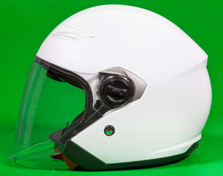 Open face white motorcycle helmet with attached face shield, side view, a green background