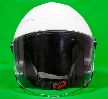 Open face white motorcycle helmet with attached face shield, front view, green backgroundの写真素材