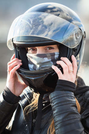 Close up view at Caucasian woman motorcyclist wearing crash black helmet on her headの写真素材
