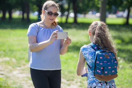 Mom recording video with her young daughter with smartphone in park