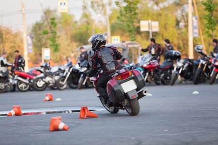 Motorcycle driver riding bike on urban square using it as motordrome, rear viewの写真素材