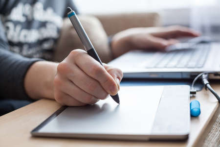 Close-up view at pen of drawing board painting on surface, woman illustrator in work