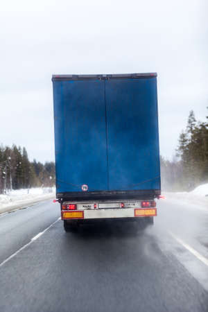 Freight truck driving along winter asphalt road, rear viewの写真素材