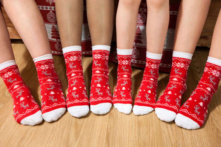 Line from human feet wearing red Christmas socks, adults and children legs arranged together