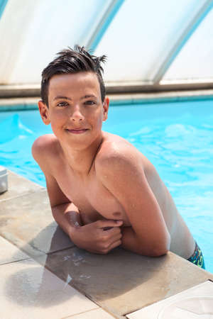 Happy and smiling teenage boy swimmer portrait when standing in swimming poolの写真素材