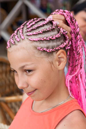 Portrait of caucasian girl with pink dreadlocks hairstyle, holding her plait with handsの写真素材