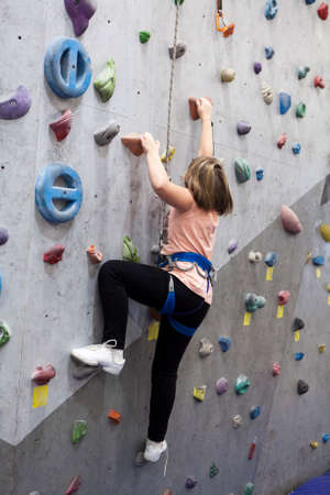 Pretty Caucasian girl climbering artificial rock-climbing wallの写真素材