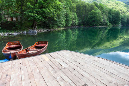 View at the green water and evergreen forest on Biogradskoe lake from wooden pier. Biogradska Gora national park. Montenegro, Europaの写真素材