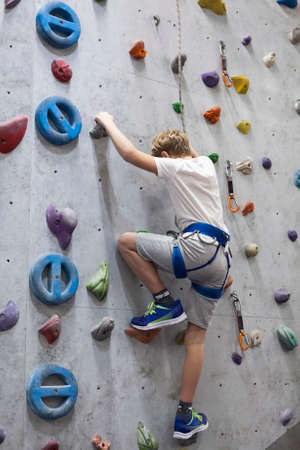 Activity of rock-climbing on artificial climbing walls, Caucasian boy with safety lineの写真素材