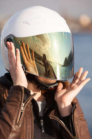 Close up portrait of unrecognizable European female motorcyclist with white open face helmet with mirrored tinted visorの写真素材