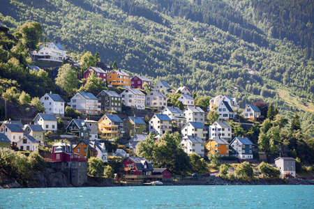 Colourful wooden houses for living on mountain slope near Norwegian fjord, Odda town, Hordaland county, Norwayの写真素材