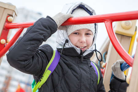 Playful Caucasian young girl walking on playground at cold winter day, looking at camera and laughingの写真素材