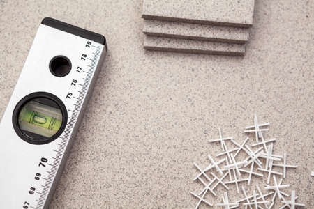 Carpenter's level and plastic crosses for tile laying, small cut pieces on floorの写真素材