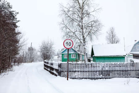 Countryside winter road with speed limit sign, Russian village, Russiaの写真素材