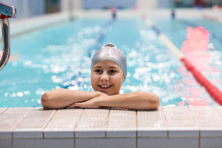 Young swimmer girl. Portrait of ten years old athlete in swimming cap in poolの写真素材