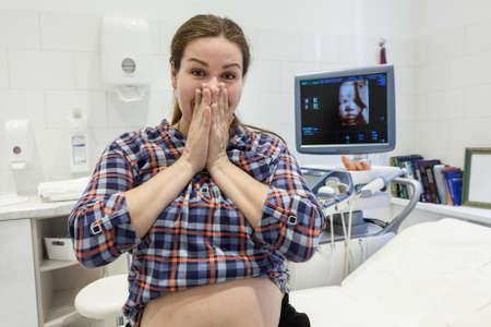 Pregnant woman amazed after watching image of her baby at ultrasonography, monitor screen with 3d...