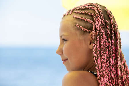 Teenage girl with dreadlocks, side view, copyspace against blue seaの写真素材