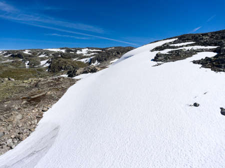 Snow lies in mountains on the sides of mountain road Aurlandsvegen, the Aurland, Norwayの写真素材
