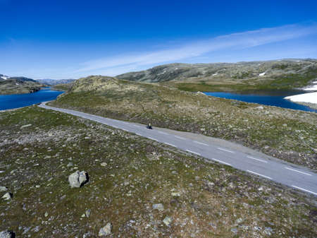 Motorcycle driving on asphalt road in Norwegian highlands. Snow road Aurlandsvegen is in the Aurland, Norwayの写真素材