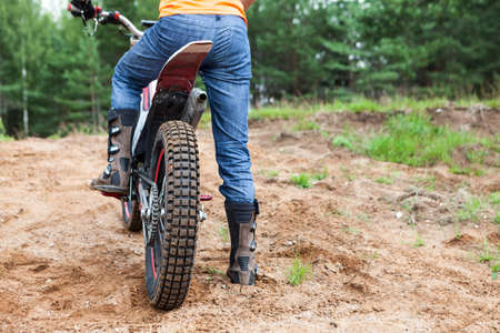 Mototrial rider standing on motorcycle in sand. Extreme sports on motorcross motorcycles. Copyspace