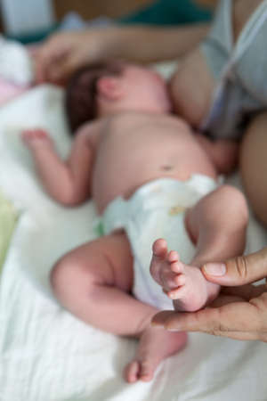 Newborn baby and mother during breast-feeding, woman holding small leg of infant in handの写真素材