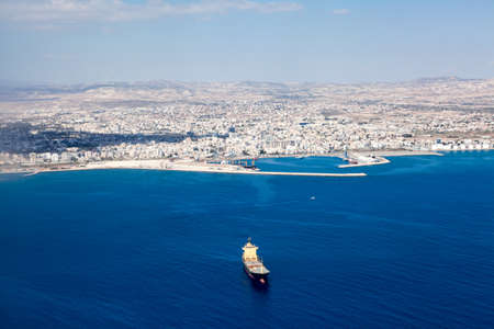Aerial view at Larnaca city and Main Harbor in Cyprus island. Dry-cargo freighter coming from port