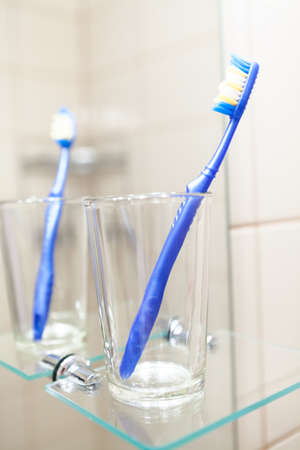 Blue dental cleaning brush is in glass in bathroomの写真素材