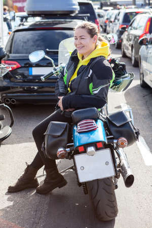 Woman motorcyclist sitting on her motorcycle, standing in queue to boarding on ferryboat, cars, bikes and other vehicles waiting their turn to enter the shipの写真素材