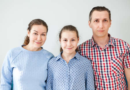 Three people Caucasian family with dad, mom and daughter portrait, grey background, looking at cameraの写真素材
