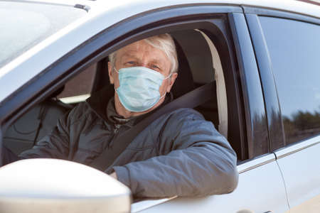 Senior man a driver using surgical mask to prevent virus infection, a taxi driverの写真素材