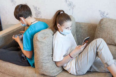 Children are in online interactions during coronavirus pandemic, kids wearing safety masks staying...