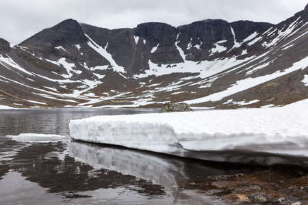 Mountain lake with glacier, snow melting is in Khibiny Massif at spring season. The Kola (Kolsky)...