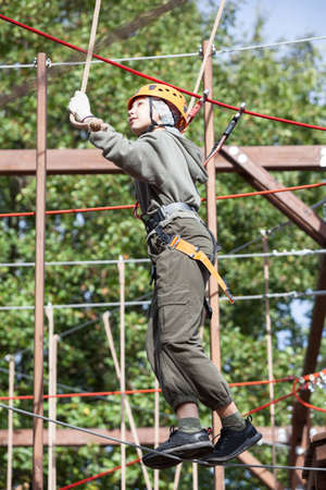 Athlete girl stepping on a rope in outdoor climbing park